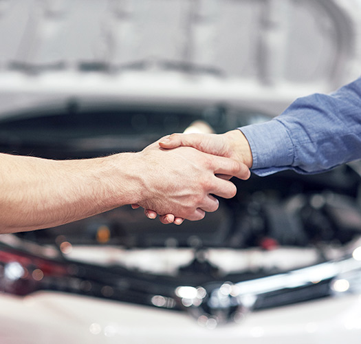 Hand Shake in front of an automobile.